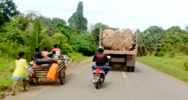 truck bermuatan batu besar melintasi jalan raya dari Desa Momujiu